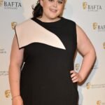 Scottish actress Sharon Rooney posing in a promotional photo for the BBC reality show Celebrity Traitors series two, Scottish actress Sharon Rooney known for My Mad Fat Diary and Barbie looking toward the camera, Official cast announcement graphic for Celebrity Traitors featuring actress Sharon Rooney, Sharon Rooney standing in front of a dark castle backdrop for The Traitors promotional material